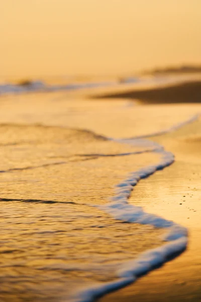 Onde che lambiscono sulla spiaggia al tramonto . — Foto Stock