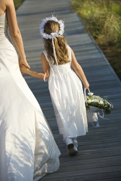 Bruid en bloemenmeisje aan promenade — Stockfoto