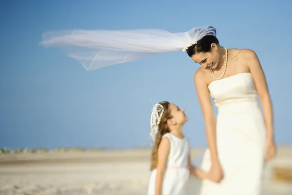 Невеста и цветочница на пляже — стоковое фото
