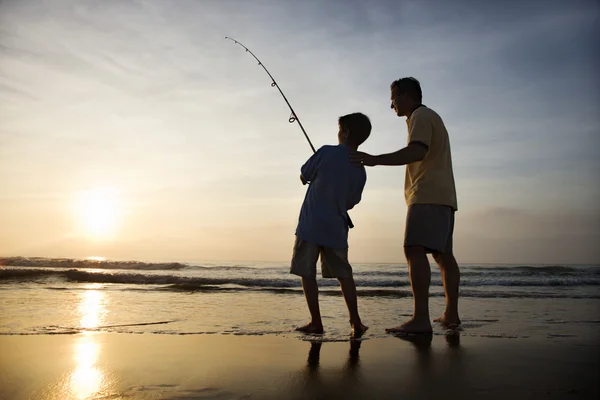 男人和年轻男孩在冲浪钓鱼 免版税图库照片