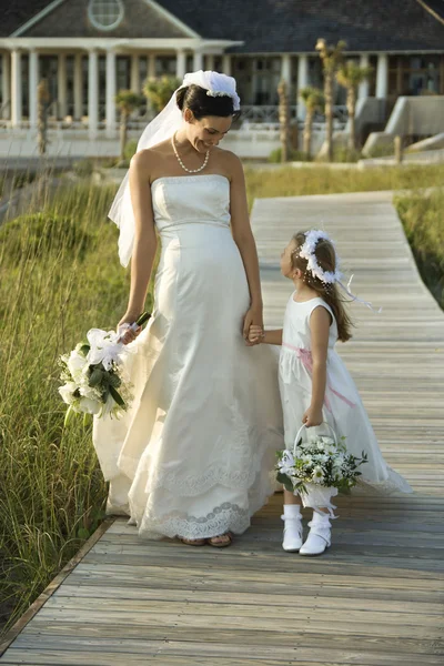 Bride and flower girl walking. Royalty Free Stock Images