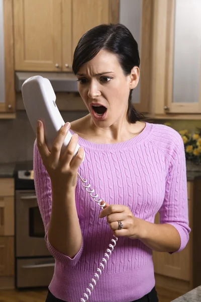 Frau hält Telefon ungläubig in der Hand Stockbild