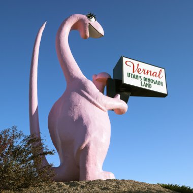 Pink dinosaur holding sign. clipart
