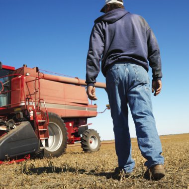 Farmer walking toward combine. clipart