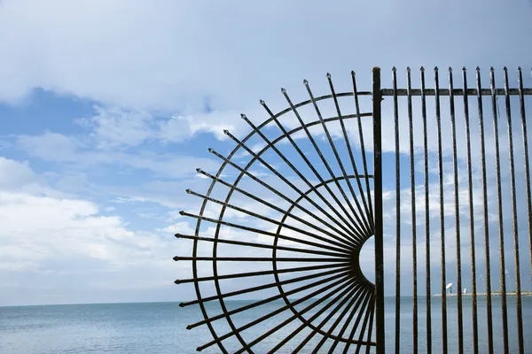 Wrought iron fence by ocean. — Stock Photo, Image