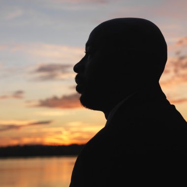 African-American man standing by water at sunset in Washington, DC, USA. clipart