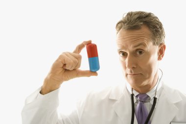 Doctor holding pill. clipart