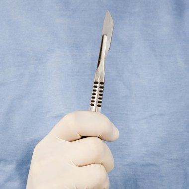 Surgeon holding scalpel. clipart