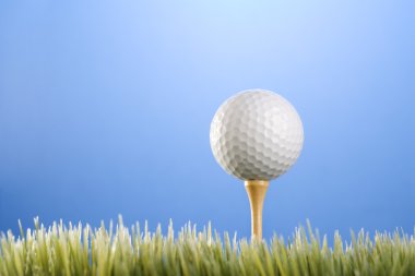 Golfball on tee in grass. clipart