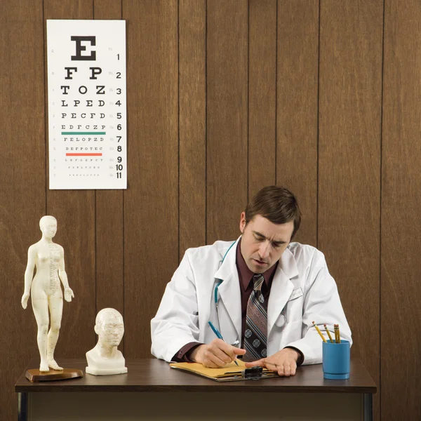 Doctor writing at desk. — Stock Photo, Image