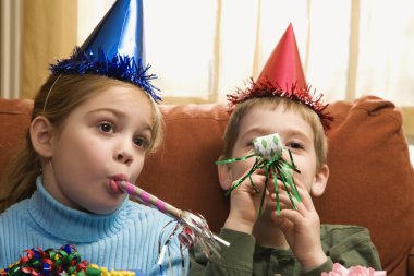 Children blowing noisemakers. clipart