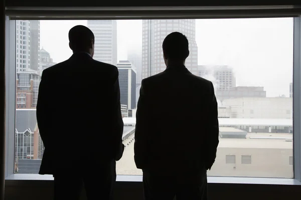 Uomini d'affari che guardano fuori da una finestra — Foto Stock