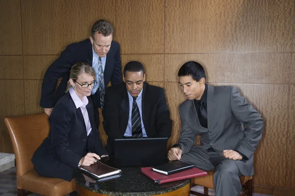 Företagare samlades runt en laptop — Stockfoto