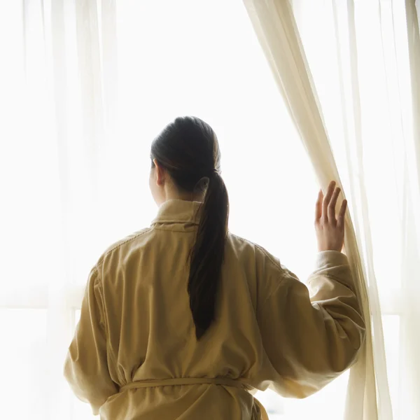 Женщина смотрит в окно . — стоковое фото