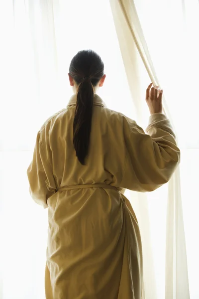 Женщина смотрит в окно . — стоковое фото