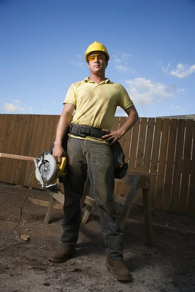 Trabajador de la construcción de pie con sierra — Foto de Stock