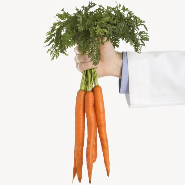 Doctor holding carrots. — Stock Photo, Image