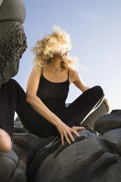Mujer agachada sobre rocas . — Foto de Stock