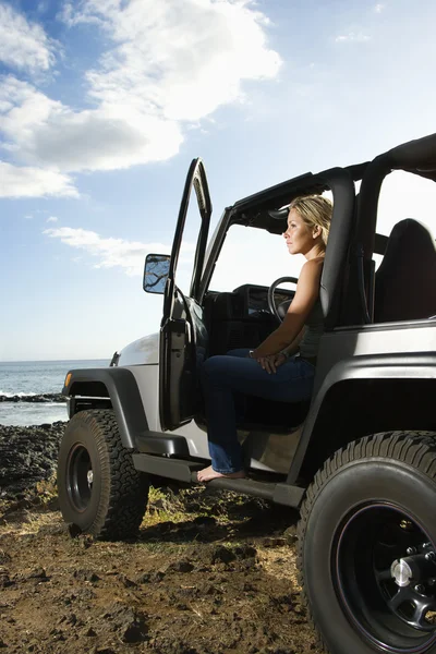 Жінка сидить у позашляховика на пляжі — стокове фото