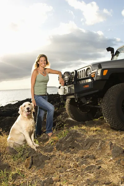 Женщина и собака на внедорожнике на пляже — стоковое фото