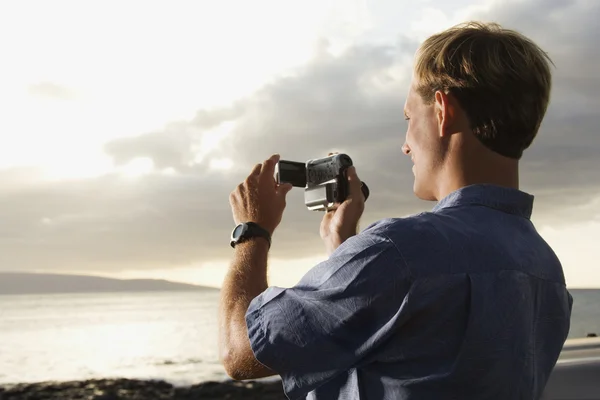 Homem usando câmera de vídeo na praia — Fotografia de Stock