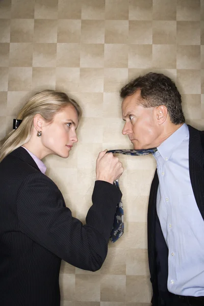 Wütende Geschäftsfrau zieht Mann die Krawatte Stockfoto