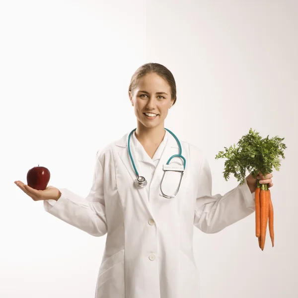 Arzt, Apfel und Karotten. Stockbild