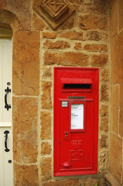 Красный британский почтовый ящик на каменной стене — стоковое фото