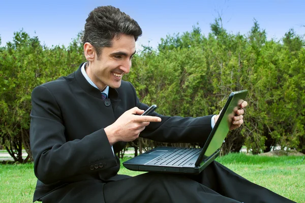 Hombre joven con teléfonos celulares y portátil . — Foto de Stock