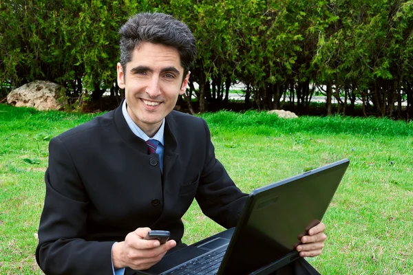 Jonge man met mobiele telefoons en laptop. — Stockfoto