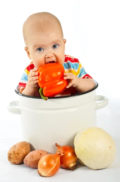 Дитина сидить у великій каструлі з овочами . — стокове фото