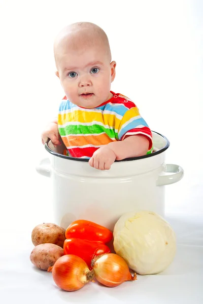Bebê sentado na panela grande com legumes . — Fotografia de Stock