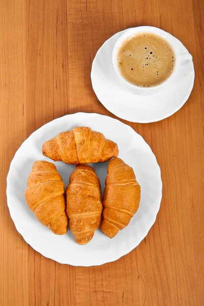 Frisch gebackene Croissants und eine Tasse Kaffee. — Stockfoto