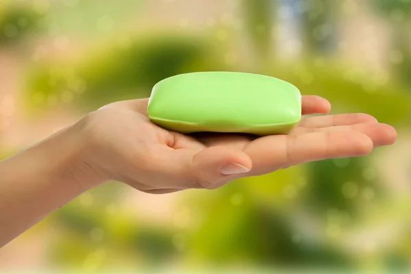 Bar mýdlo v rukou na zeleném pozadí abstraktní. — Stock fotografie