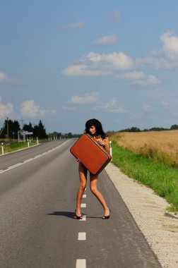 Sexy brunette on the road holding bag clipart