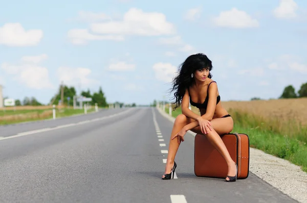 Bruna con valigia in strada, autostrada . Foto Stock