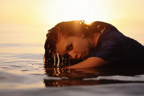 Femme dans l'eau au coucher du soleil — Photo