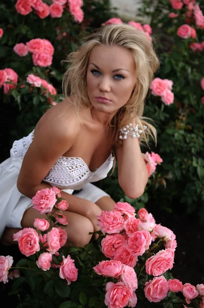 Schöne Frau inmitten von Rosen — Stockfoto