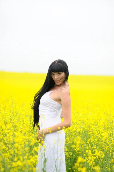 Mooie brunette onder gele bloemen — Stockfoto