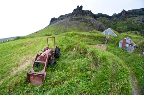 Dağların altında terkedilmiş eski paslı traktör — Stok fotoğraf