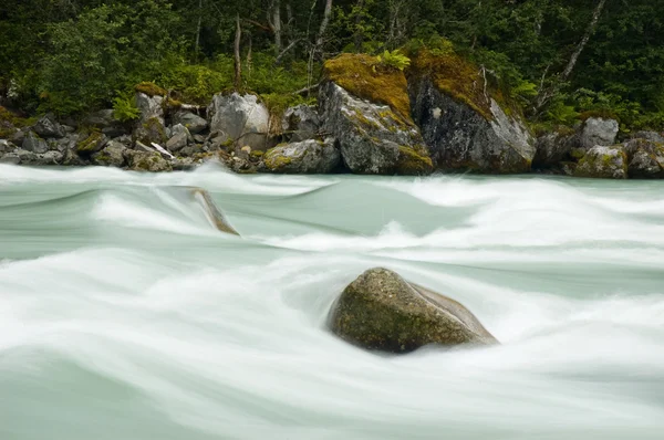 Камінь у річці, тривалий рух води розмитий — стокове фото
