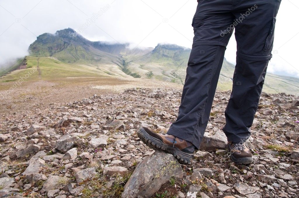 Tourist in hiking shoes standing atop the mountain