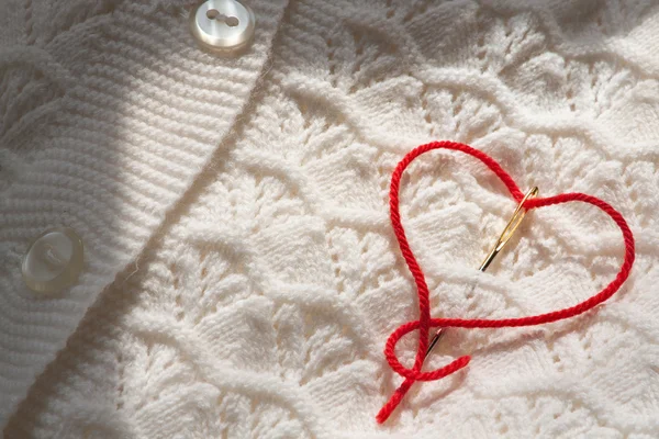 Needle with red thread in the shape of a heart — Stok fotoğraf