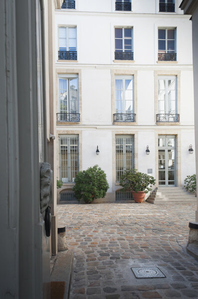 Vertical Image of a Private upscale Interior Cobblestone Courtyard and apartment building in Paris, France.