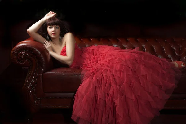 Žena v červené barvě na pohovce — Stock fotografie