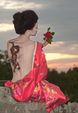 Geisha with dragon tattoo at sunset clipart