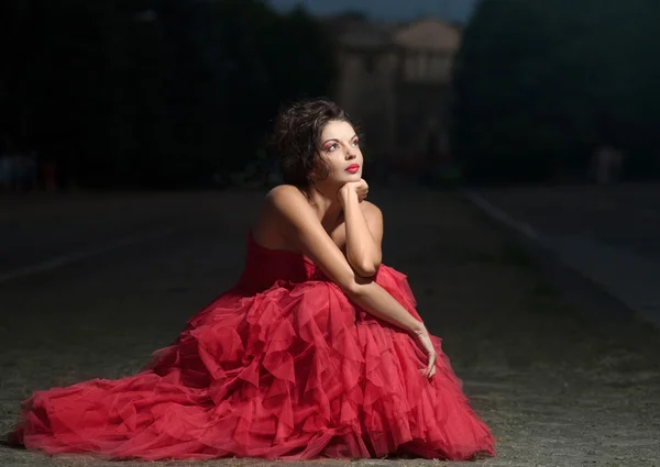 Mooie vrouw in rode jurk bij zonsondergang — Stockfoto