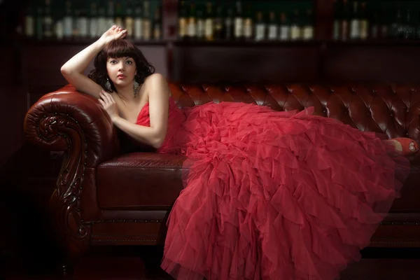 Mulher de vermelho no sofá — Fotografia de Stock