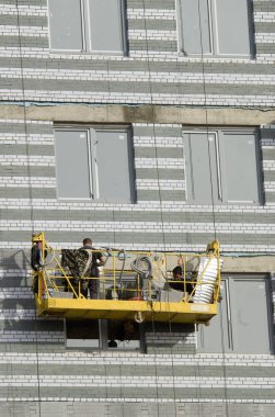 Builders in suspended platform on facade clipart
