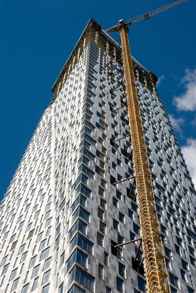 Construction of skyscraper with hoisting crane — Stockfoto